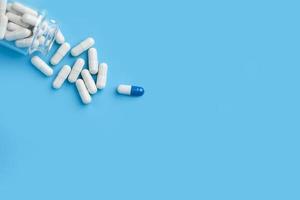 Pills spilling out of pill bottle of a glass bottle. on a blue background. photo