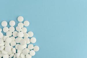 White round pills scattered on blue background. Medicine flat lay. photo