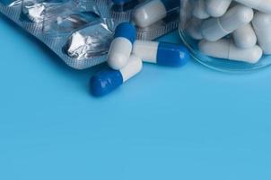 cápsulas de pastillas de medicina en blister y en la botella sobre fondo azul con espacio de copia. foto