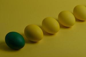 cuatro huevos amarillos y uno verde sobre fondo amarillo foto