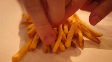 primer plano de manos tomando patatas fritas de una mesa