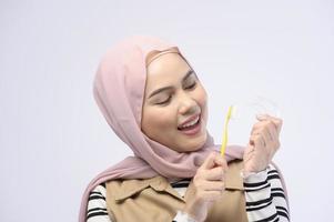 una joven musulmana que usa cepillo de dientes con dientes hermosos, concepto de atención de la salud dental foto