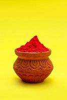 Indian festival Holi concept Red colour bowl on yellow background. photo