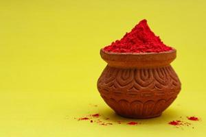 Indian festival Holi concept Red colour bowl on yellow background. photo