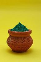 Indian festival Holi concept green colour bowl on yellow background. photo