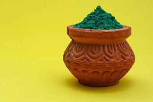 Indian festival Holi concept green colour bowl on yellow background. photo