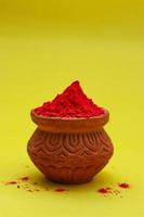 Indian festival Holi concept Red colour bowl on yellow background. photo