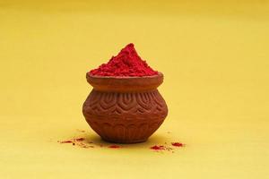 Indian festival Holi concept Red colour bowl on yellow background. photo