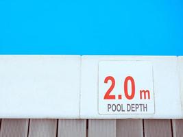 The edge of the swimming pool with the table with information of the depth in English language. Sport, safety, recreation and relax concept. photo