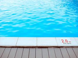 The edge of the swimming pool with the table with information of the depth in English language. Sport, safety, recreation and relax concept. photo