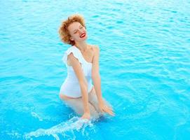 smiling redhead woman portrait enjoying life in white swimming suit in the swimming pool photo