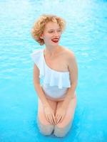 smiling redhead woman portrait enjoying life in white swimming suit in the swimming pool photo