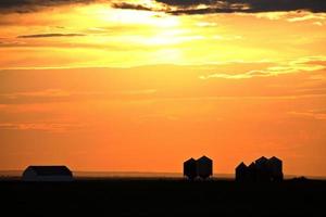 puesta de sol iluminando edificios agrícolas en el pintoresco saskatchewan foto