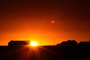 Sun rising behind a Saskatchewan farm building photo