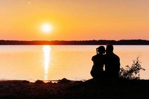 Romantic couple on the beach at colorful sunset on background photo