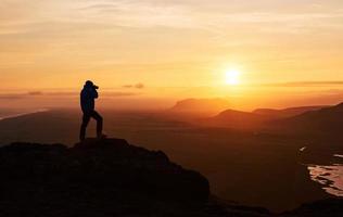 Nature photographer with digital camera on top of the mountain. photo