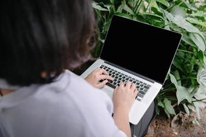 mujer independiente creativa que usa una computadora portátil en un café con planta de interior, mujer de negocios en línea que trabaja en una computadora portátil mientras está sentada en un café interior. trabajo en laptop y comunicación en línea foto