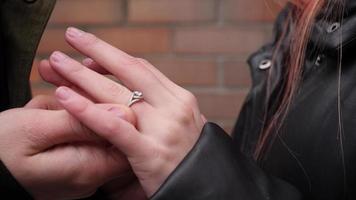 um homem usa um anel de noivado no dedo de uma mulher na rua video