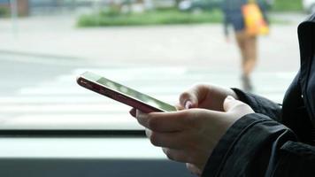 Nahaufnahme von Frauenhänden, die den Bildschirm eines Mobiltelefons berühren, das in einem Bus sitzt video