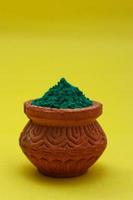 Indian festival Holi concept green colour bowl on yellow background. photo