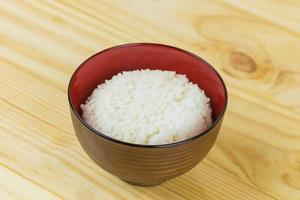 Cooked jasmine rice in white bowl on wooden table and dark background with copy space,high calories food,Top view. photo