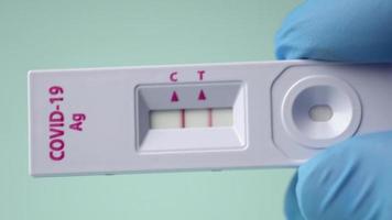 tiro macro da mão de um médico mostrando um cassete de teste expresso pcr de antígeno covid-19 com um resultado positivo. video