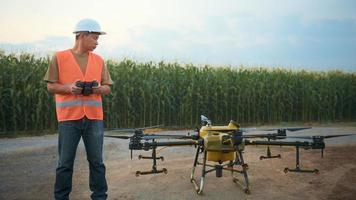 ingegnere maschio che controlla i droni che spruzzano fertilizzanti e pesticidi su terreni agricoli, innovazioni ad alta tecnologia e agricoltura intelligente video