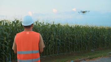 ingegnere maschio che controlla i droni che spruzzano fertilizzanti e pesticidi su terreni agricoli, innovazioni ad alta tecnologia e agricoltura intelligente video