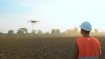 ingegnere maschio che controlla i droni che spruzzano fertilizzanti e pesticidi su terreni agricoli, innovazioni ad alta tecnologia e agricoltura intelligente video