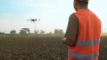ingegnere maschio che controlla i droni che spruzzano fertilizzanti e pesticidi su terreni agricoli, innovazioni ad alta tecnologia e agricoltura intelligente video