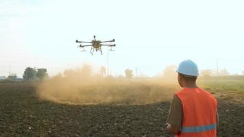 ingeniero masculino que controla la fumigación de fertilizantes y pesticidas con drones sobre tierras de cultivo, innovaciones de alta tecnología y agricultura inteligente video