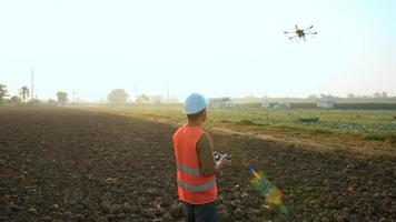 ingeniero masculino que controla la fumigación de fertilizantes y pesticidas con drones sobre tierras de cultivo, innovaciones de alta tecnología y agricultura inteligente