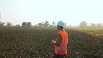 Male engineer controlling drone spraying fertilizer and pesticide over farmland,High technology innovations and smart farming video