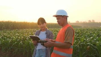 un ingénieur masculin fournit une consultation et donne des instructions à un agriculteur intelligent avec un drone pulvérisant des engrais et des pesticides sur les terres agricoles, des innovations de haute technologie et une agriculture intelligente