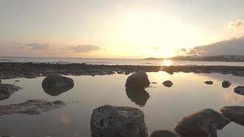 una playa rocosa durante la puesta de sol video