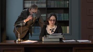 Boss Drinking Coffee or Tea while Dictating Text to Write to Secretary. Female Using Retro Typing Machine in the Office video