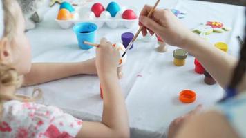 niña con su madre pintando huevos de pascua con color naranja. fotografía de cerca video