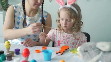 Mother Advises Daughter How to Coloring Wooden Eeaster Bunny and Little Girl Deligently Coloring It. Slow Motion