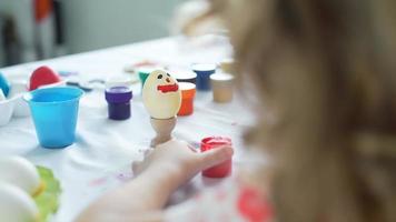 Little Girl Painting Funny Face on the Easter Egg with Brush video