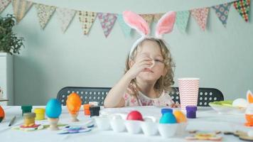 bambina che mangia uovo di Pasqua sbucciato e acqua potabile dalla tazza di carta