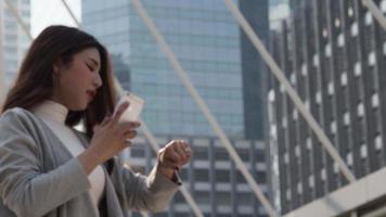 empresária asiática olhando relógios e falando no smartphone. video