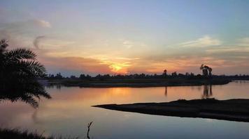 puesta de sol en la orilla del río. agua que fluye en el río en bangladesh. video
