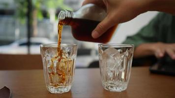 Kaffeetasse, Kaffee in ein Glas mit Eis gießen, kalt gebrühter Kaffee, Zeitlupe in 4k video