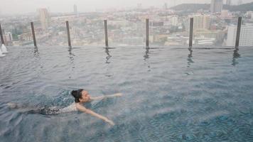 zeitlupenaufnahme, junge asiatische frauen schwimmen im dachpool, glückliche und entspannte zeit beim schwimmen