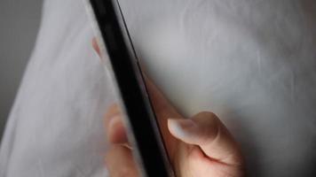 Primer plano de mensajes de texto a mano usando un teléfono inteligente en la cama en casa video