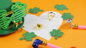 St.Patrick 's Day. Leprechaun cap and shamrock leaves on orange background. Carnival. View from above. Copy space.