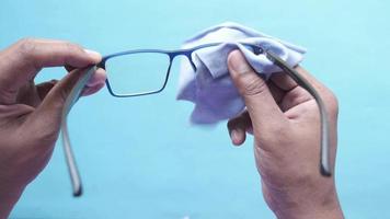 cleaning eyeglass with tissue close up video