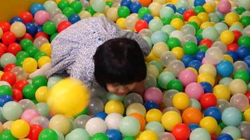 vista superior da menina criança brincando com muitas bolas de plástico coloridas video