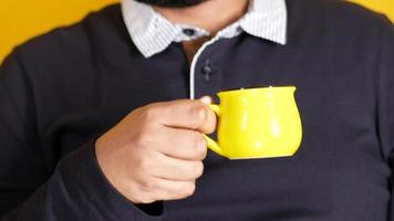 young man holding yellow color coffee mug video