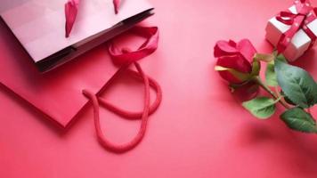 Draufsicht auf Geschenkbox und Rosenblüte auf farbigem Hintergrund
